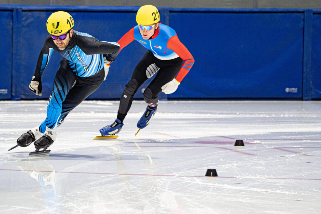 Two athletes skating with helmet on the rink