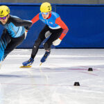 Two athletes skating with helmet on the rink