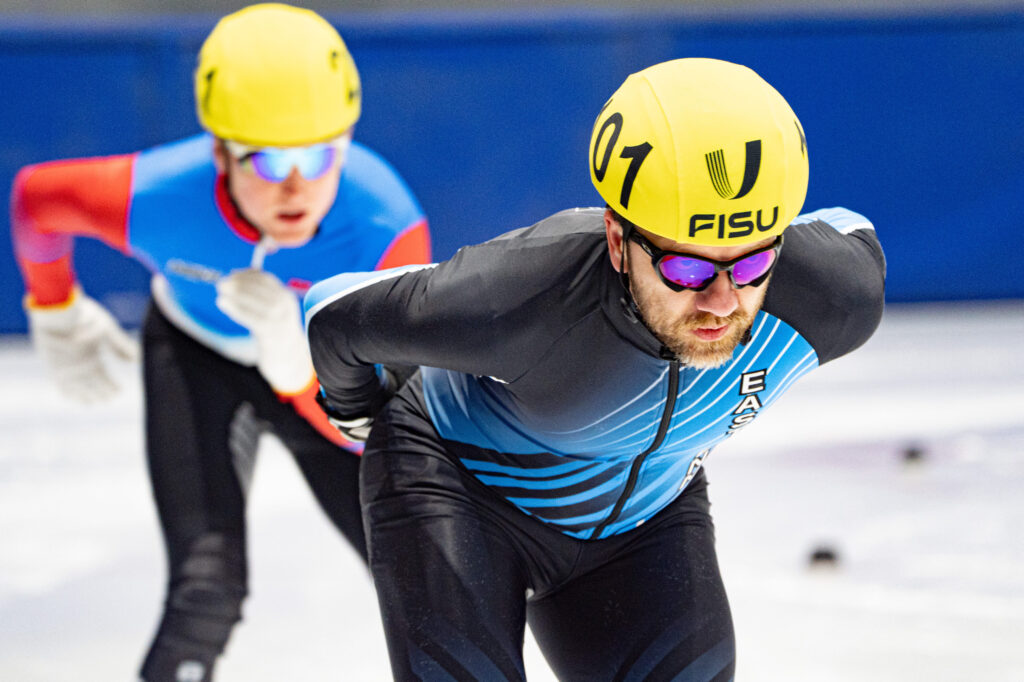 Two athletes skating with helmet on the rink