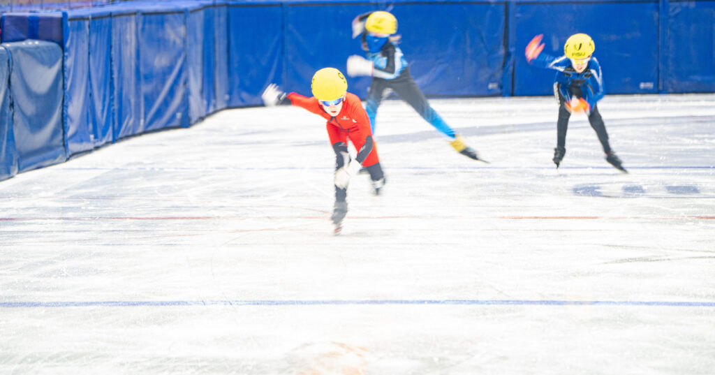 A group of athletes skating with helmet on the rink