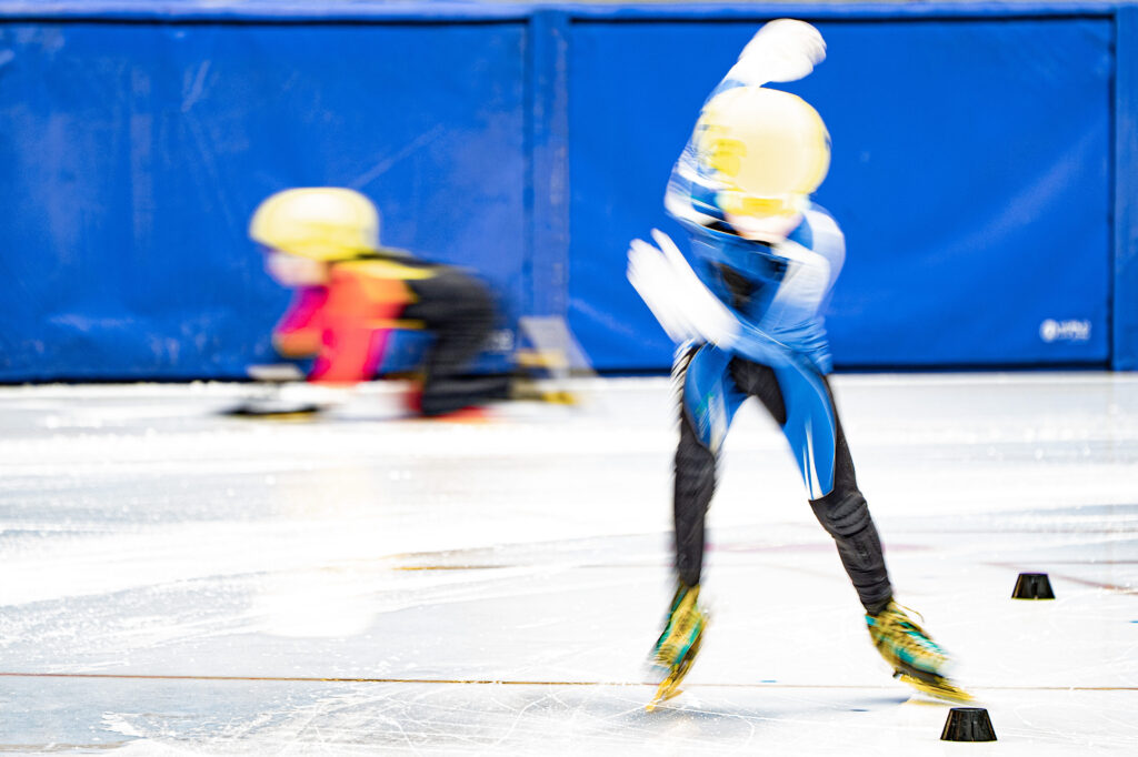 Two athletes skating with helmet on the rink