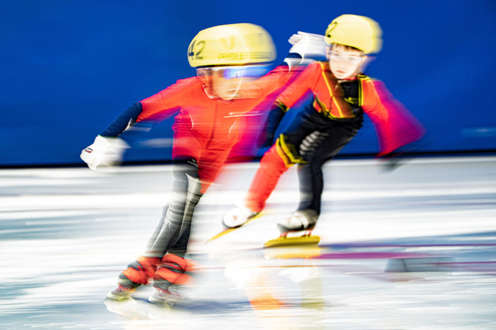 Two athletes skating with helmet on the rink