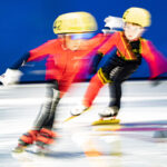 Two athletes skating with helmet on the rink