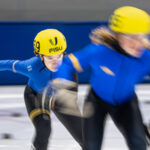 Two athletes skating with helmet on the rink