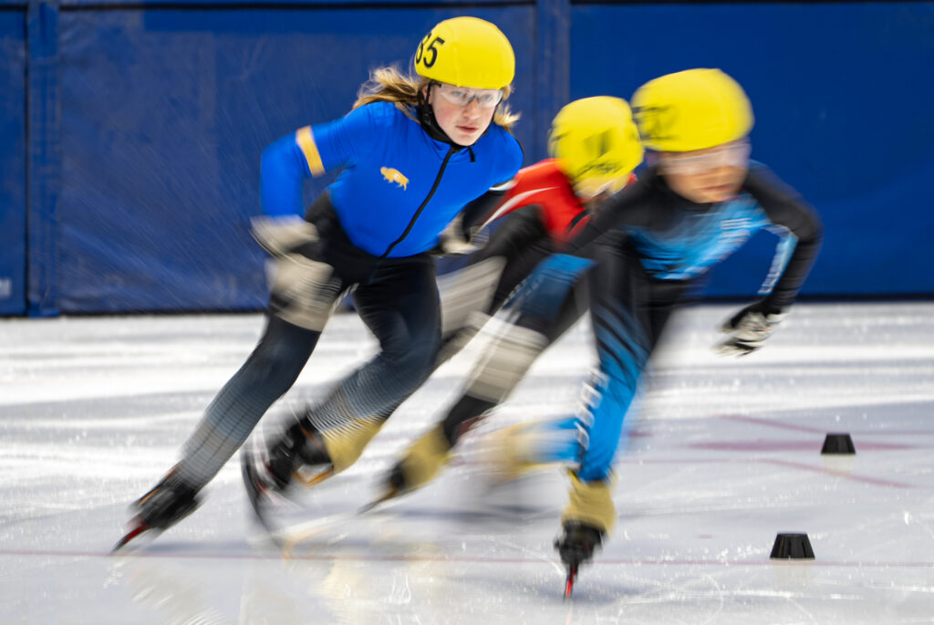 Two athletes skating with helmet on the rink