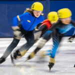 Two athletes skating with helmet on the rink