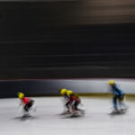 A group of athletes skating with helmet on the rink
