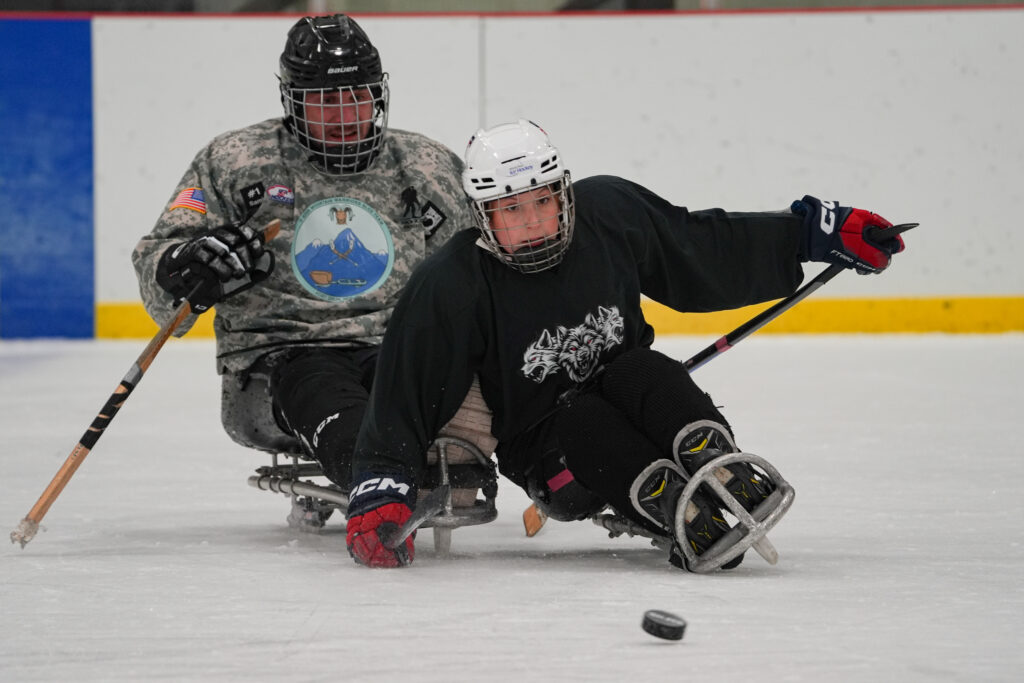 Two athletes skating with helmet on the rink