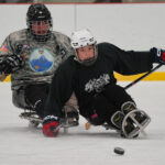 Two athletes skating with helmet on the rink