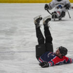 A group of athletes competing field hockey with helmet