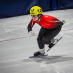 An athlete competing field hockey with helmet