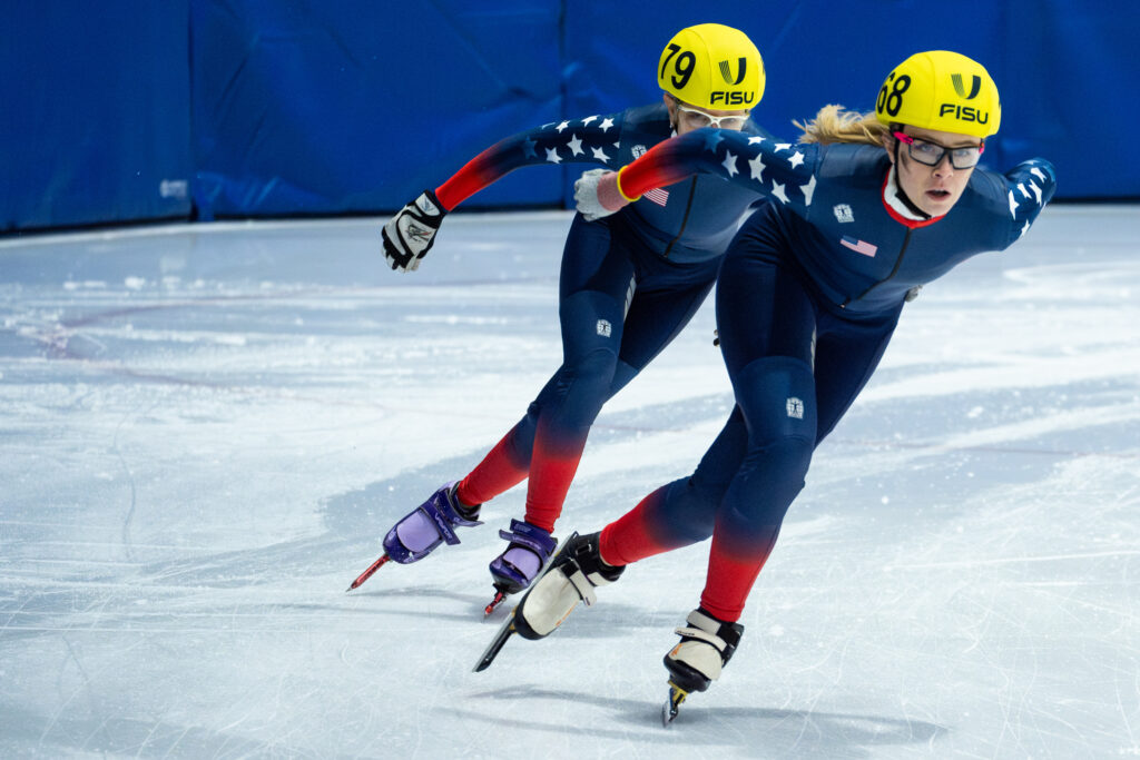 Two athletes skating with helmet on the rink