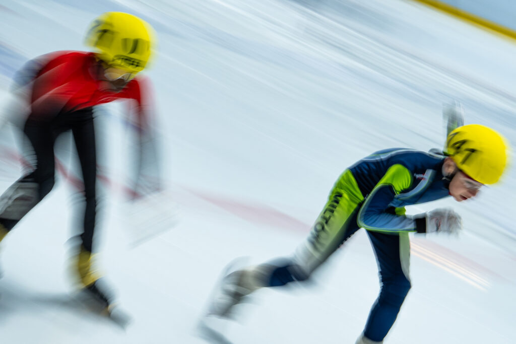 Two athletes skating with helmet on the rink