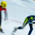 Two athletes skating with helmet on the rink