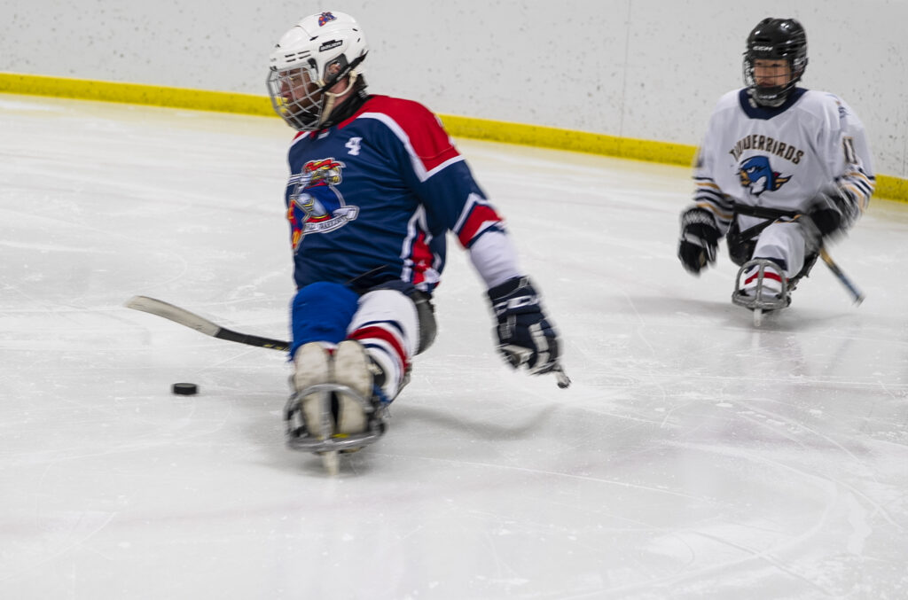 Two athletes skating with helmet on the rink