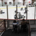 A group of athletes competing field hockey with helmet
