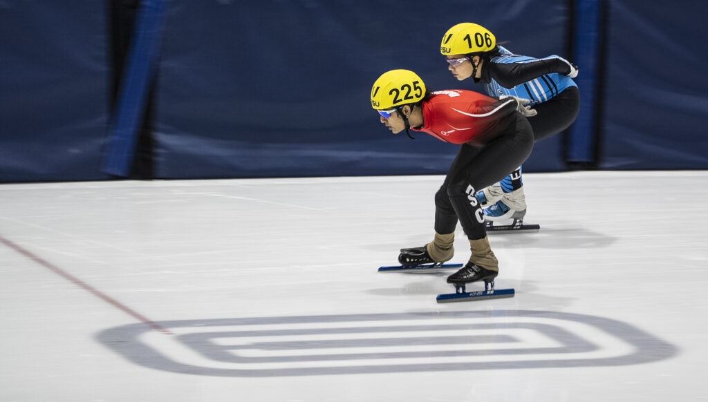 Two athletes skating with helmet on the rink