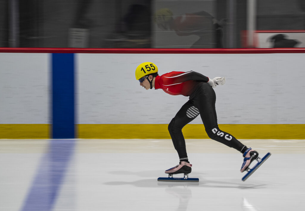 Two athletes skating with helmet on the rink