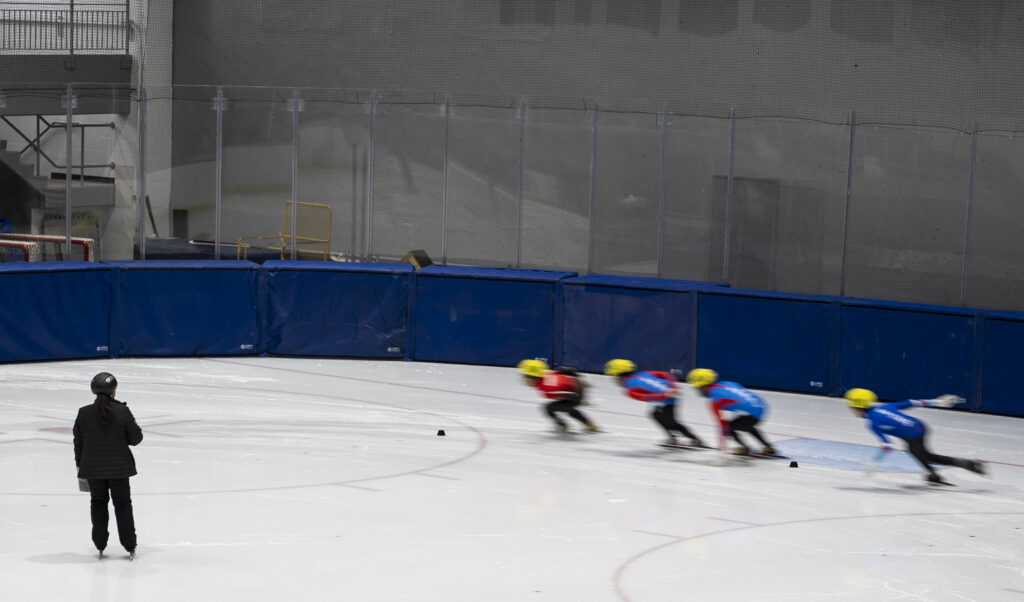 A group of athletes skating with helmet on the rink