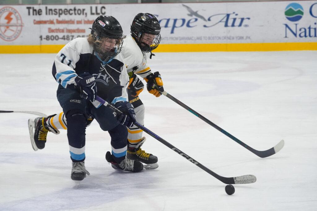 Two athletes competing field hockey with helmet