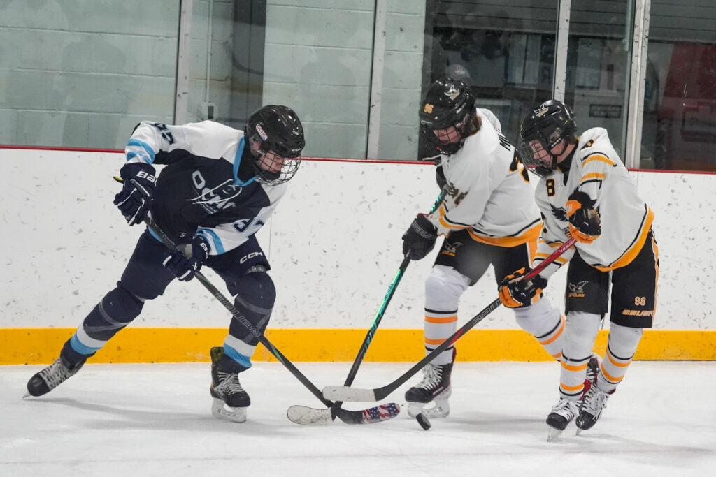A group of athletes competing field hockey with helmet