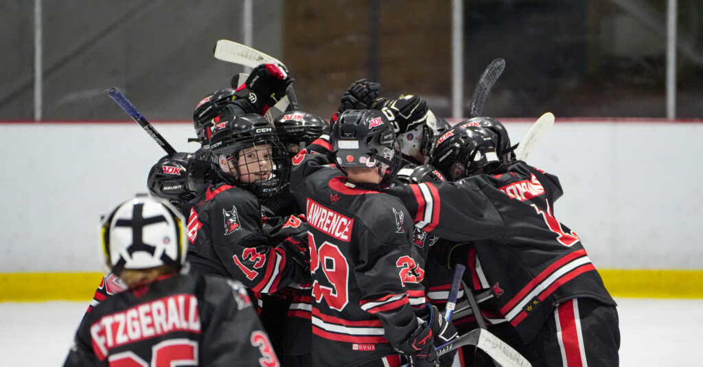 A group of athletes competing field hockey with helmet