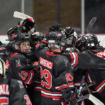 A group of athletes competing field hockey with helmet