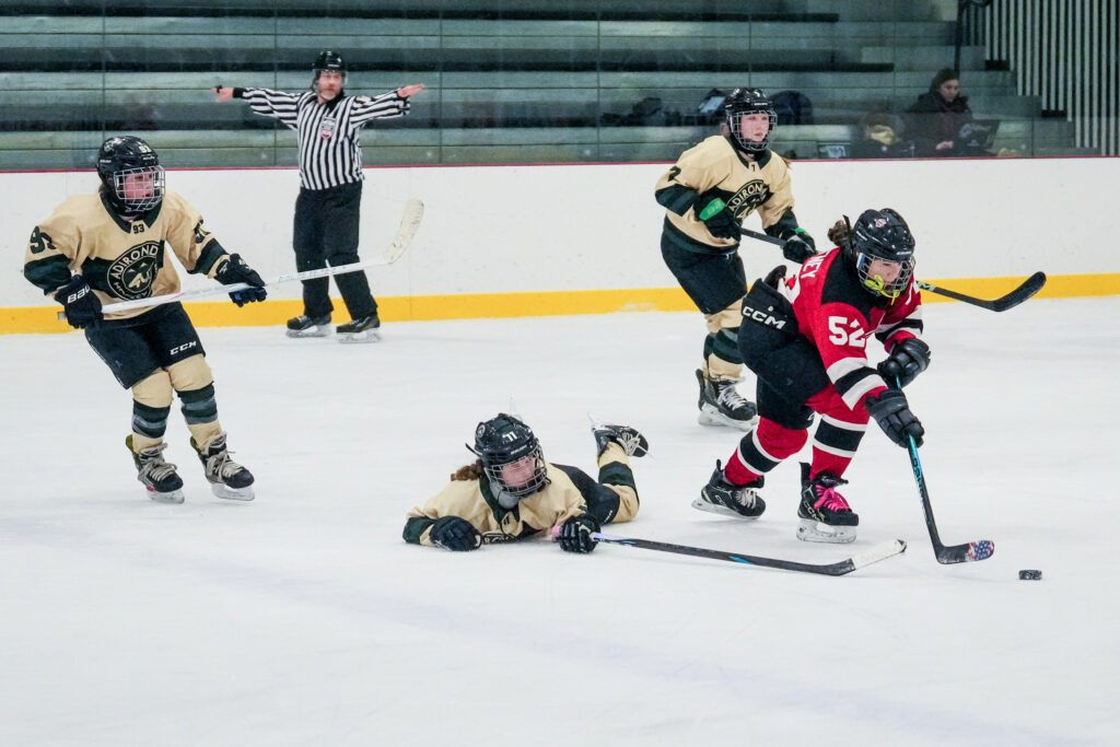 A group of athletes competing field hockey with helmet