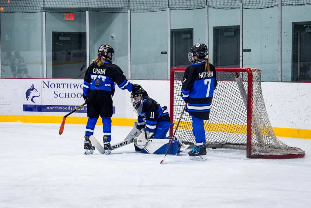 A group of athletes competing field hockey with helmet