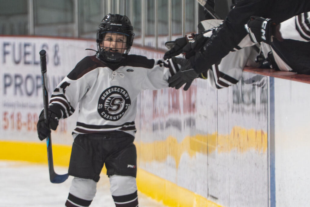 Two athletes competing field hockey with helmet