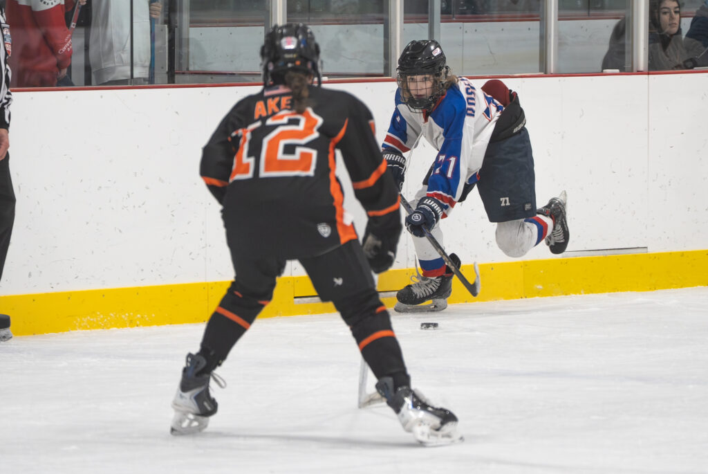 A group of athletes competing field hockey with helmet