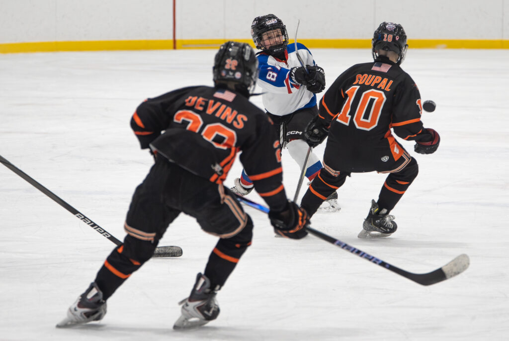 A group of athletes competing field hockey with helmet