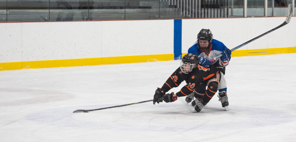 Two athletes skating with helmet on the rink