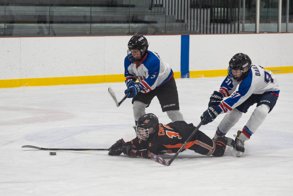 A group of athletes competing field hockey with helmet