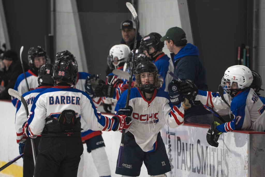 A group of athletes competing field hockey with helmet