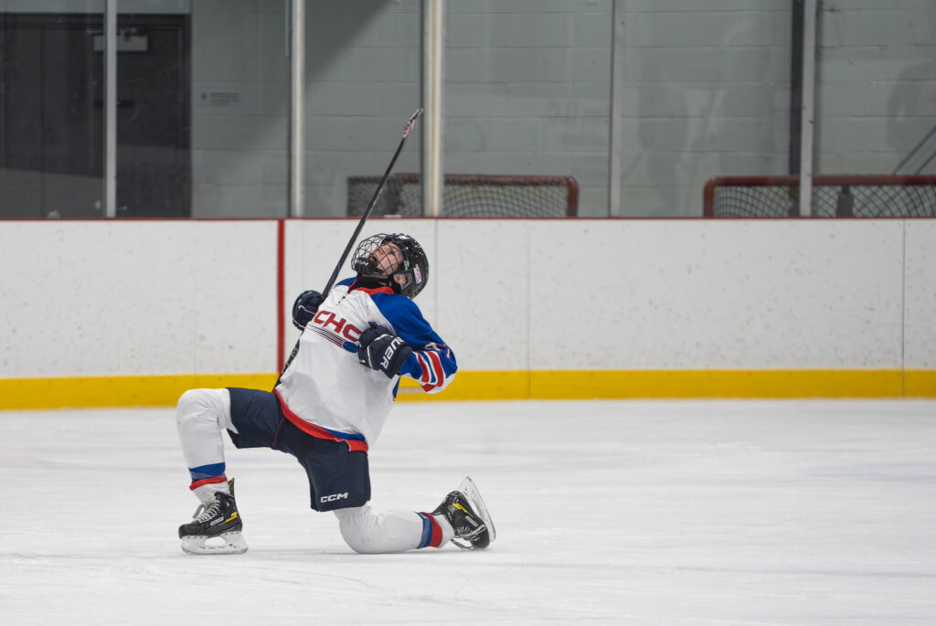 An athlete competing field hockey with helmet