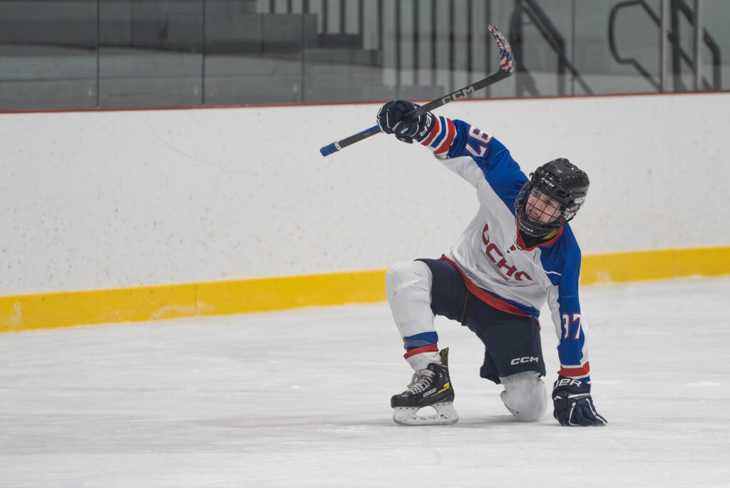 An athlete competing field hockey with helmet
