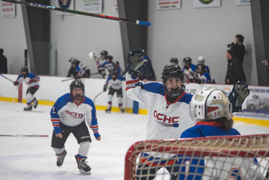 A group of athletes competing field hockey with ball and helmet