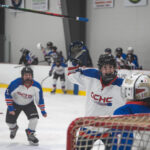 A group of athletes competing field hockey with ball and helmet