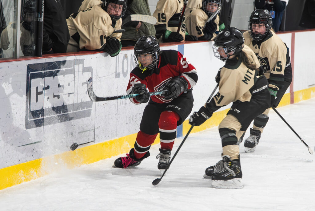 A group of athletes competing field hockey with helmet