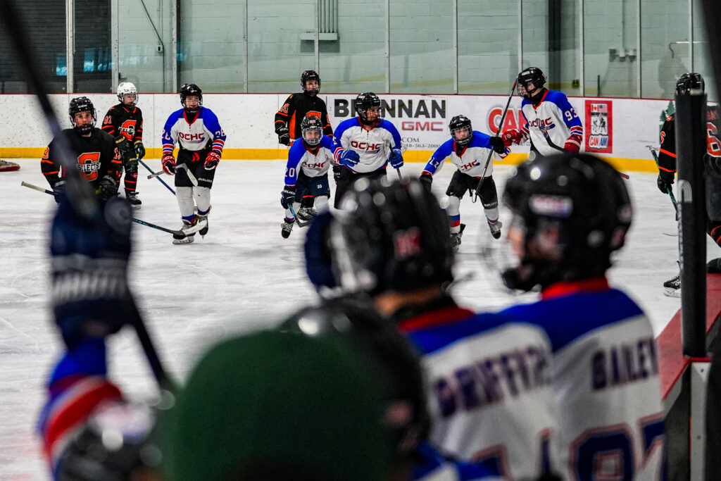 A group of athletes competing field hockey with helmet