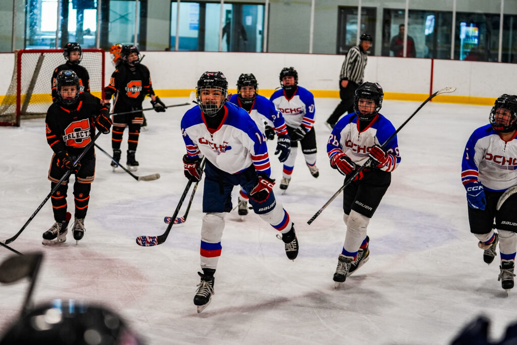 A group of athletes competing field hockey with helmet