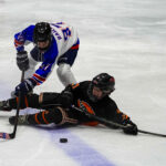 Two athletes skating with helmet on the rink