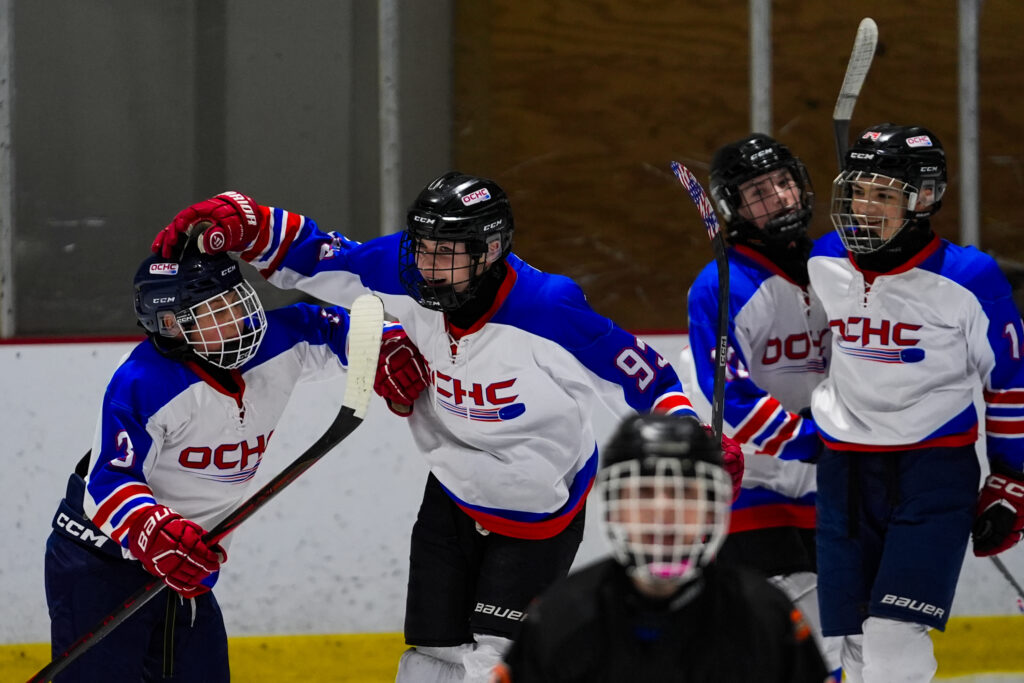 A group of athletes competing field hockey with helmet