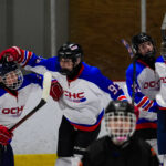 A group of athletes competing field hockey with helmet