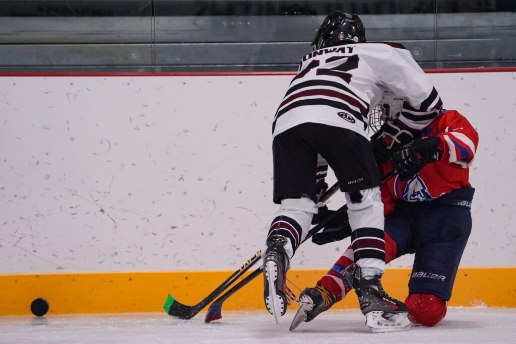 An athlete competing field hockey with helmet