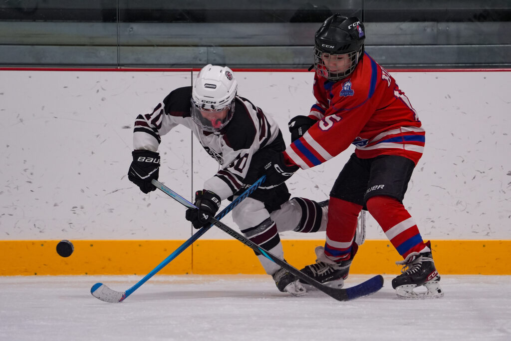 Two athletes competing field hockey with helmet