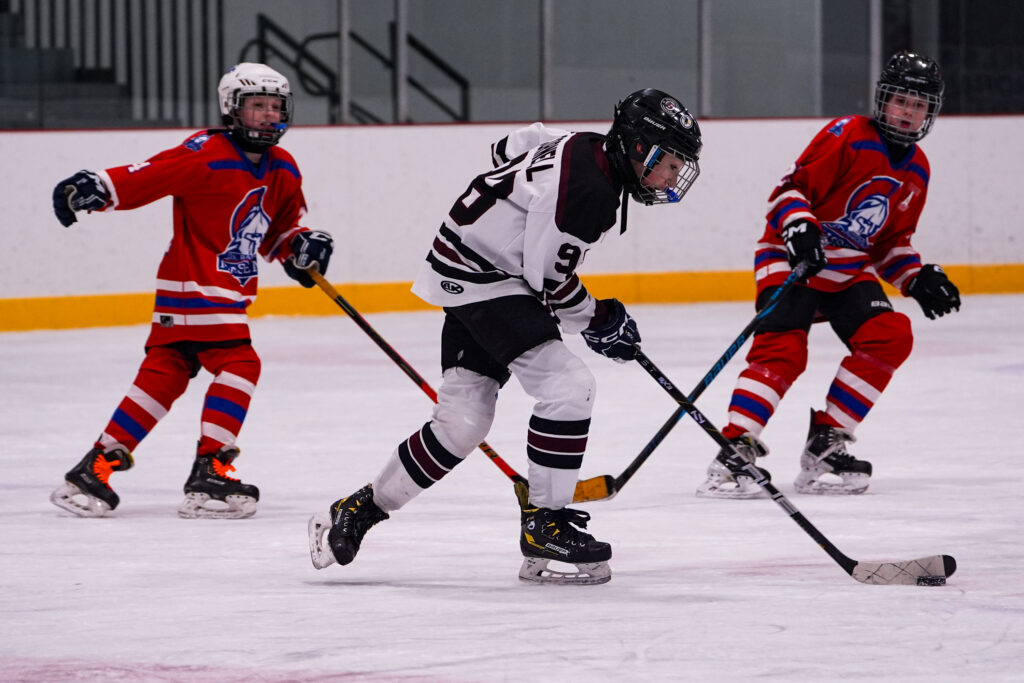A group of athletes competing field hockey with helmet