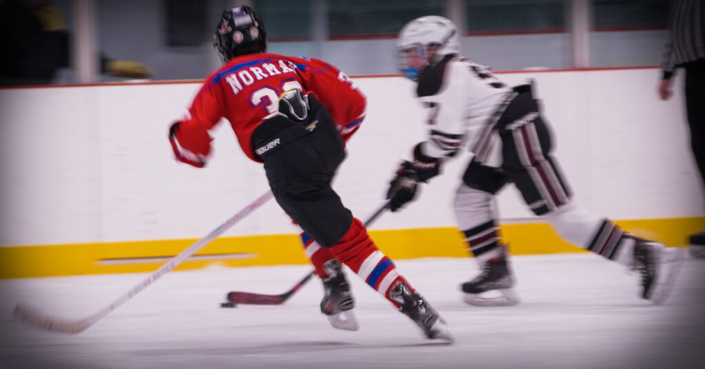 A group of athletes competing field hockey with helmet