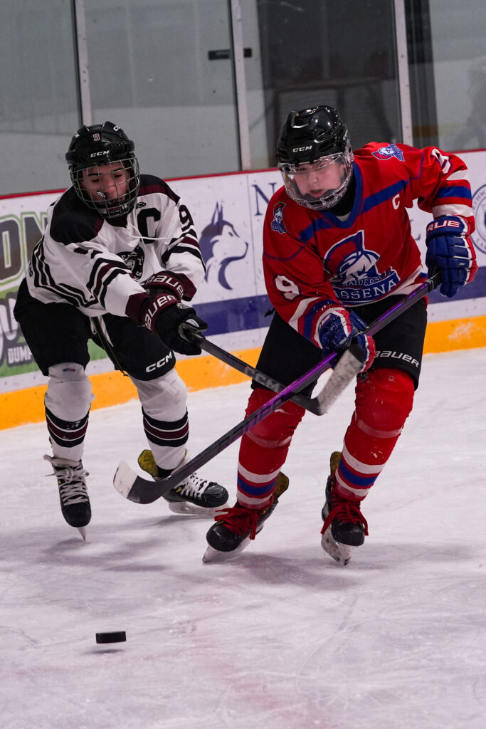 Two athletes skating with helmet on the rink